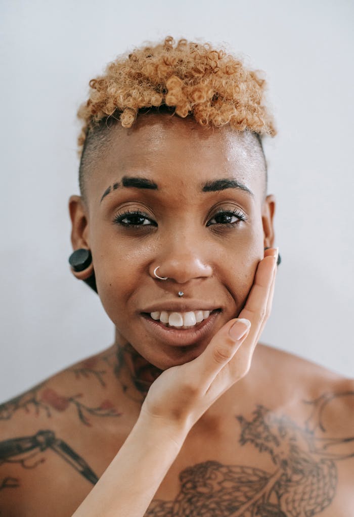 Close-up of a joyful, tattooed woman with piercings, expressing warmth and connection.